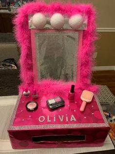 a pink vanity with makeup and accessories on it sitting on a table in front of a mirror