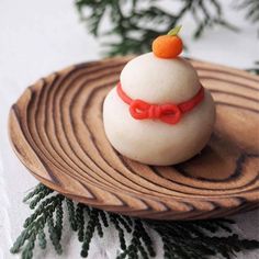 a wooden plate topped with a white frosted pastry covered in icing and a red bow