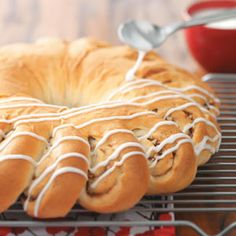 a bundt cake with white icing sitting on a cooling rack next to an apple