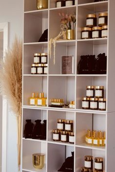 the shelves are filled with many different types of candles and body care products in gold containers