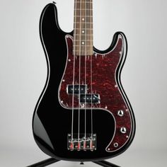 an electric bass guitar sitting on top of a black stand with red and white stripes