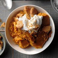 a bowl filled with food next to two spoons and a plate full of dessert