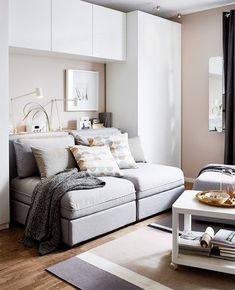 a living room filled with white furniture and lots of pillows on top of the couch