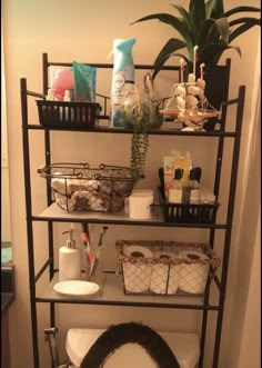 a toilet in a bathroom next to a shelf with baskets and other items on it