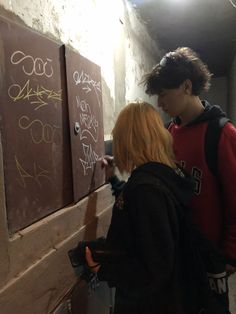 two people writing on a wall with graffiti