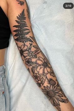 a woman laying in bed with a tattoo on her arm that has flowers all over it