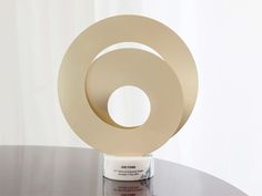 a sculpture on top of a table in front of a white wall with a circular design