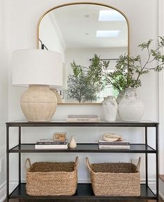 a console table with two baskets and a mirror above it in a living room area