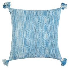 a blue and white pillow with tassels on the front, sitting against a white background