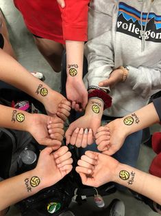 a group of people holding hands together with tattoos on their arms and wrist, in a circle