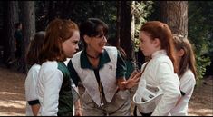 three young women talking to each other in the woods