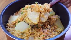 a bowl filled with rice and potatoes on top of a wooden table