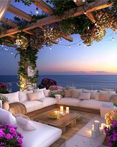 an outdoor living area with white furniture and flowers on the patio, overlooking the ocean