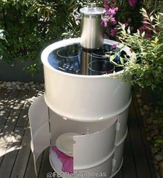 an outdoor water fountain on a deck with purple flowers in the background and greenery around it