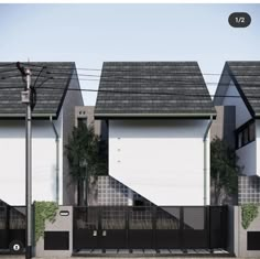 three white houses with black roof tops and fenced in area next to each other