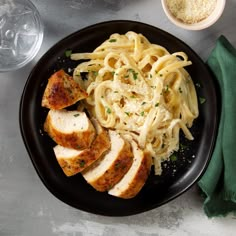 a black plate topped with meat and pasta