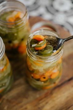 pickled vegetables in jars with spoon on wooden table