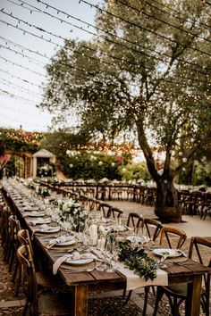 a long table is set with place settings for an outdoor dinner party in the evening