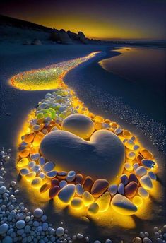 a heart made out of rocks and pebbles on the beach at night with lights in it