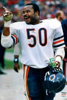 a football player is holding his helmet and giving the peace sign