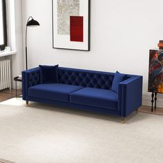 a blue couch sitting on top of a hard wood floor next to a white rug