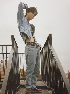 a young man standing on top of a metal hand rail