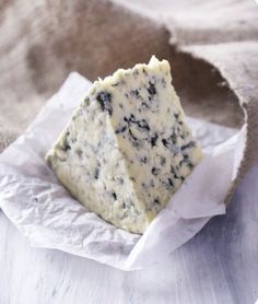 a piece of blue cheese sitting on top of a white paper wrapper next to a bag