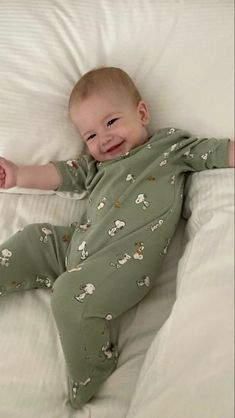 a baby laying on top of a bed with white sheets