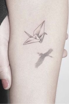 a woman's arm with an origami bird tattoo on it