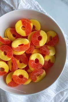 a white bowl filled with yellow and red jellopops on top of a white cloth