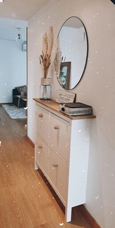 a white dresser sitting next to a mirror on top of a wooden floor