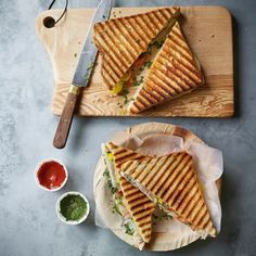 two sandwiches cut in half sitting on top of a cutting board next to a knife