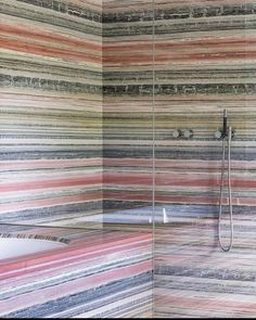 a bathroom with multicolored stripes on the wall and shower head in the corner