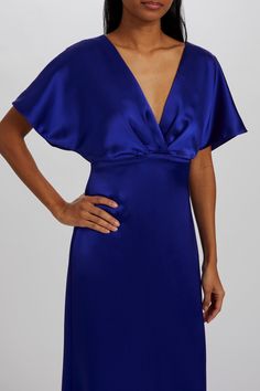 a woman in a blue dress with her hands on her hips