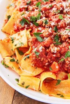 a white plate topped with pasta covered in sauce and parmesan cheese