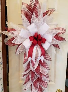 a red and white wreath hanging on the front door