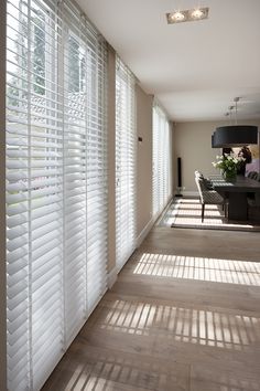 the sun is shining through the blinds in this room with wood flooring and white walls