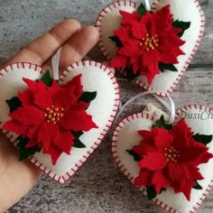 handmade heart ornaments with poinsettis on them are being held by someone