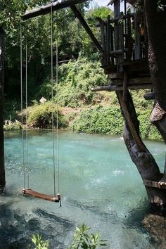 there is a swing set in the water next to a tree house on stilts