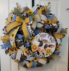 a wreath with a cow and sunflowers is hanging on the front door,