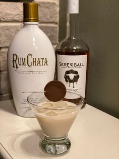 a bottle of rumchata next to an empty glass with a chocolate cookie in it