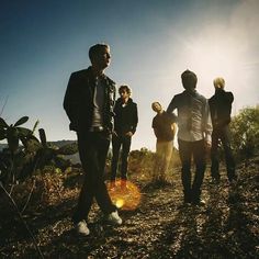 a group of young men standing on top of a dirt field under a blue sky