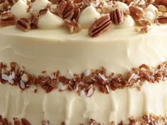 a cake with white frosting and pecans on top