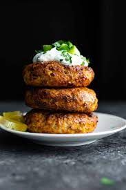 three crab cakes stacked on top of each other with sour cream and lemon wedges