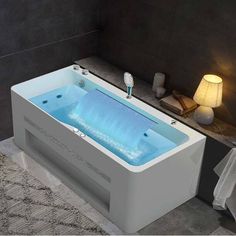 a bath tub sitting on top of a bathroom floor next to a night stand and lamp