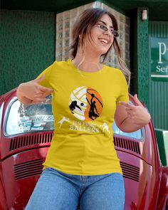 a woman wearing a yellow t - shirt is standing in front of a red car