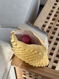 a crocheted purse sitting on top of a wooden table next to a pillow