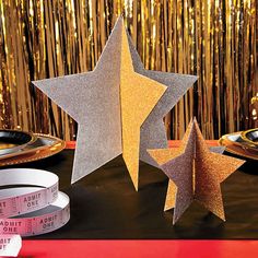 three silver and gold stars next to each other on a table with some measuring tape