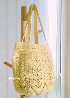 a crocheted bag hanging from a hook on a door handle in front of a window