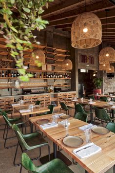 an empty restaurant with wooden tables and green chairs in front of the counter, along with hanging wicker baskets